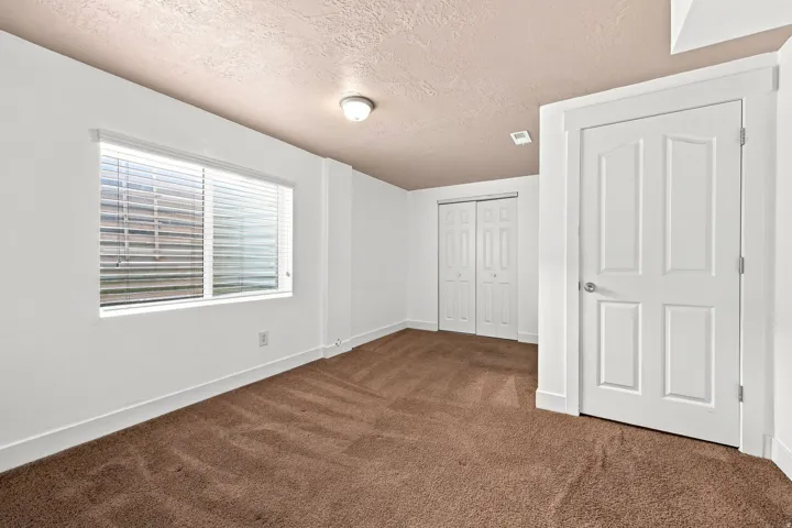 Bed 4. Brown carpet flooring, white walls, and a window with horizontal blinds