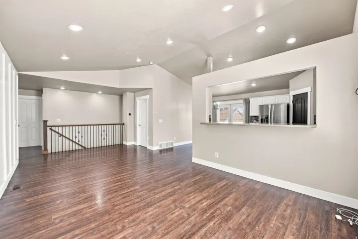 Vaulted ceiling, wood-finish flooring, recessed lighting, and a built-in breakfast bar with a stone countertop