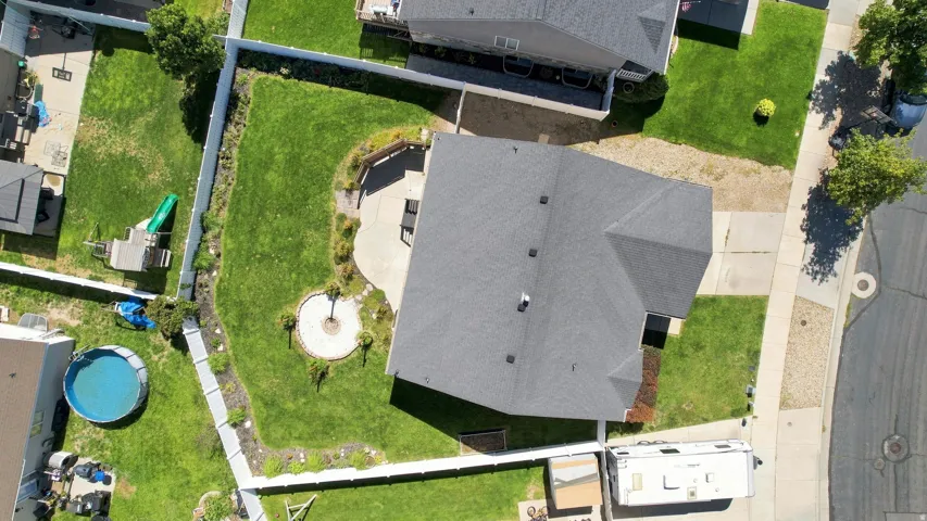 Expansive backyard with a curved concrete patio, a circular hardscaped fire pit area, and a mature tree
