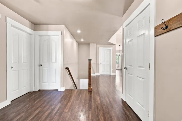 Wood-finish flooring throughout, white paneled doors, recessed ceiling lighting, and a wood handrail