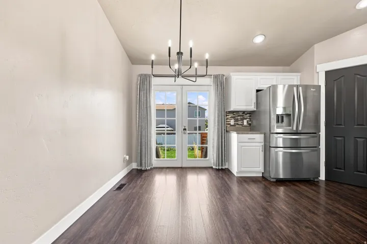 Wood-finish flooring throughout, white French doors, and a black chandelier