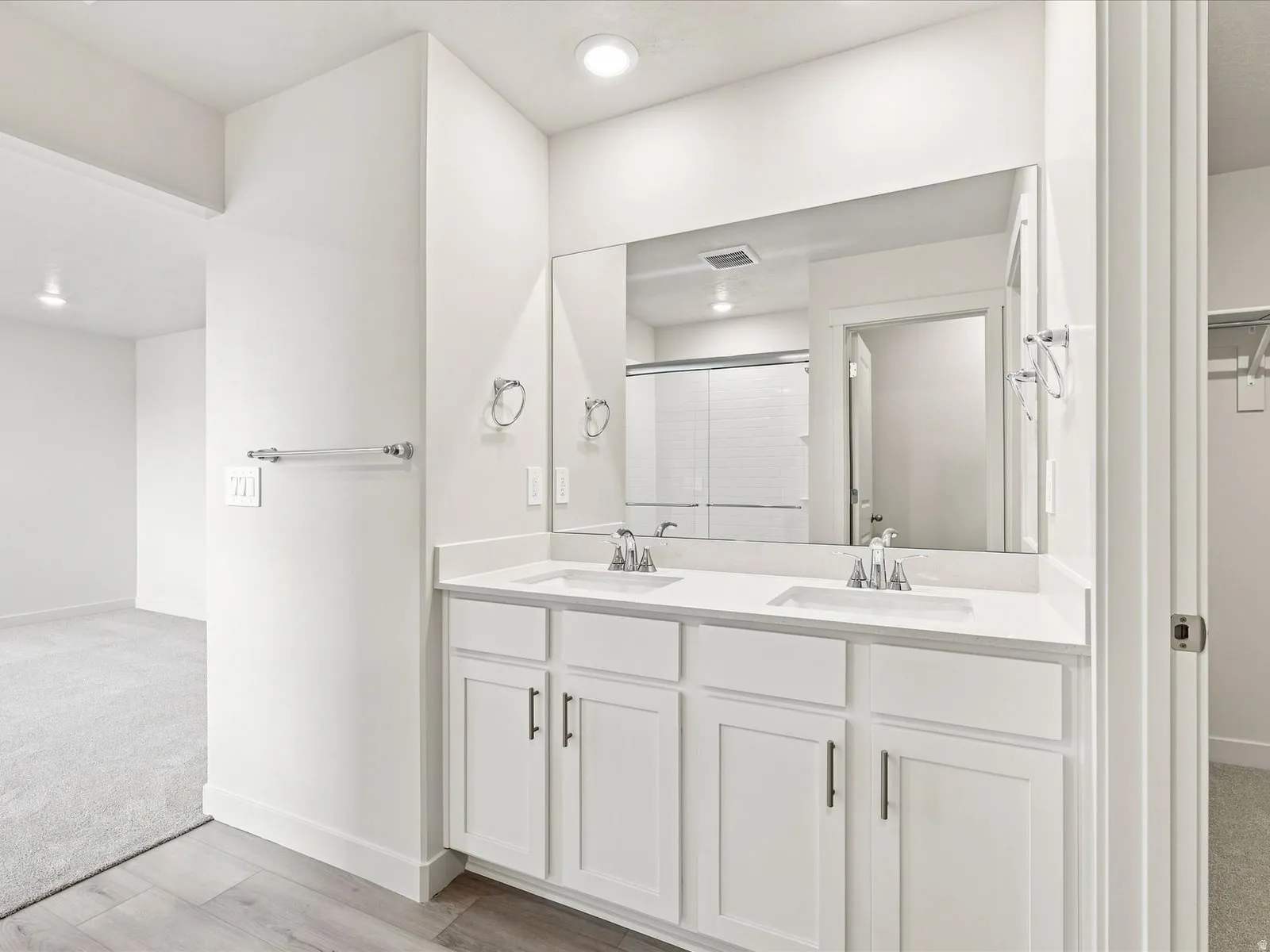 Double vanity with white cabinetry, integrated sinks, white countertops, and a wide wall-mounted mirror