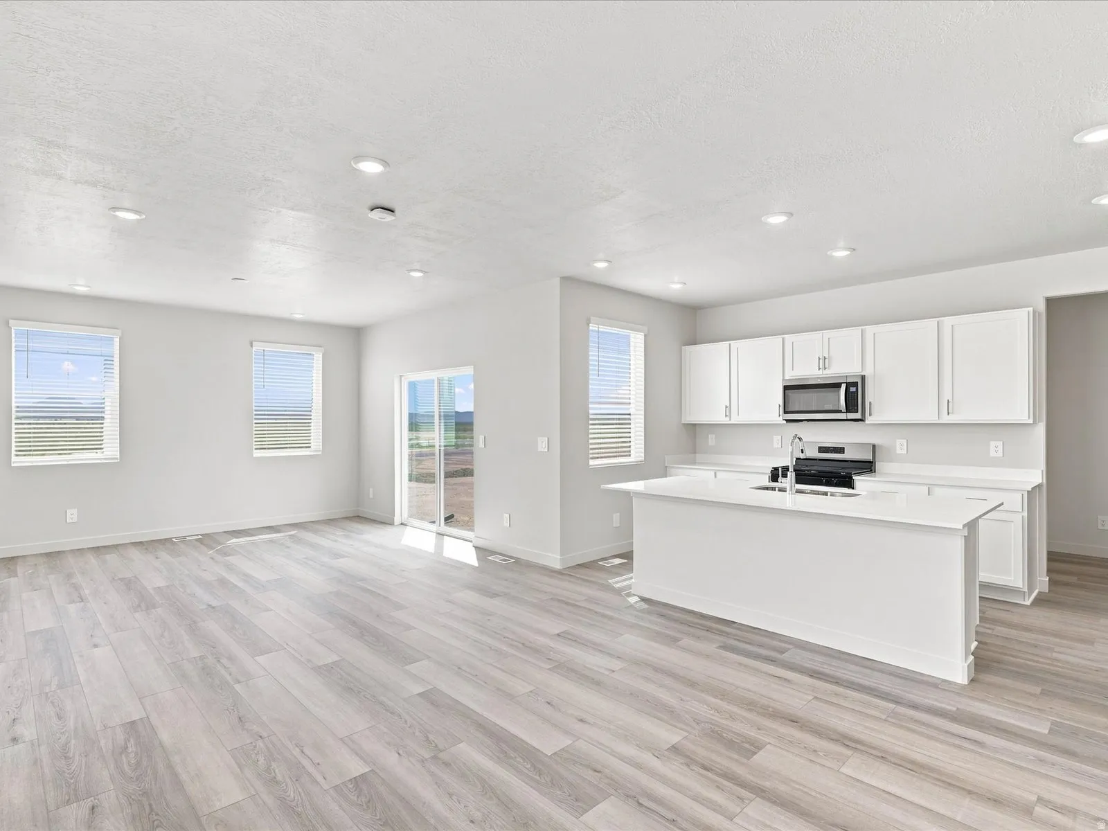 Open-concept living space featuring wood-finish flooring, recessed lighting, and a sliding glass door