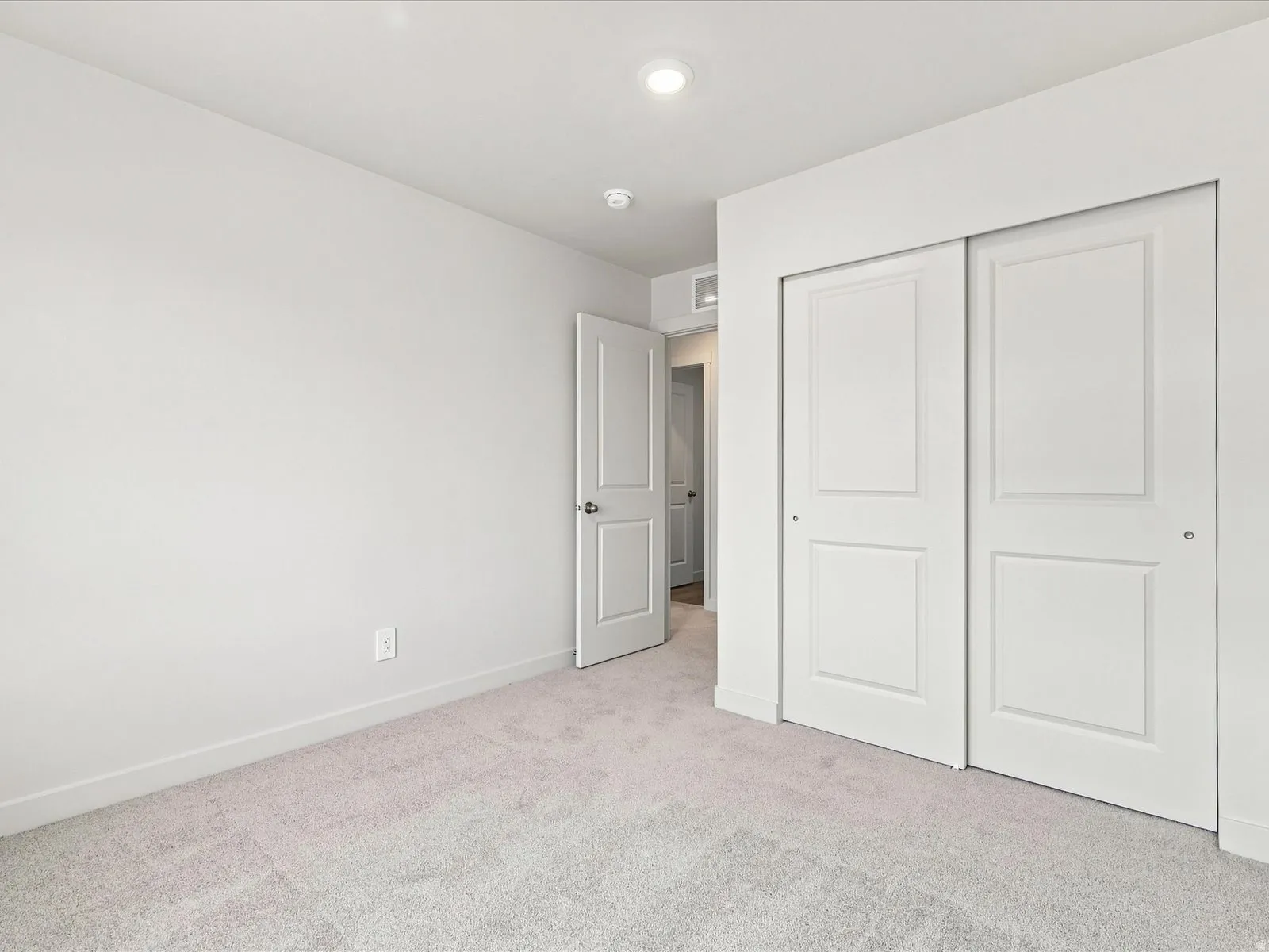 Recessed lighting, light-toned carpeting, white walls, white paneled doors, and a sliding closet door