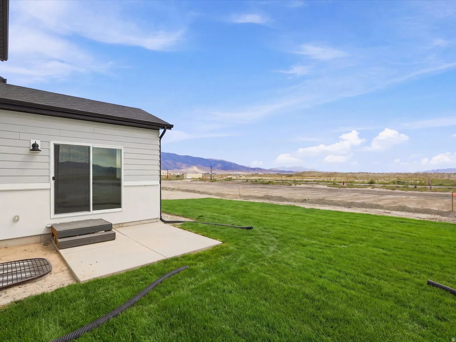 **DISCLAIMER** Landscape is only included in the front of the home. Expansive green lawn with a concrete patio and sliding glass door