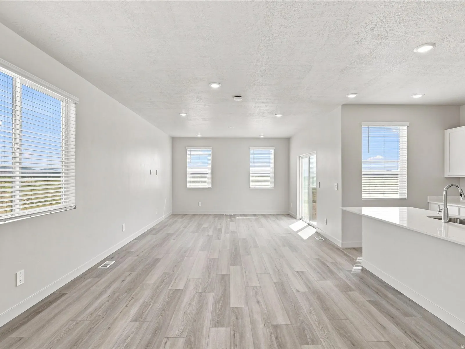 Spacious interior with neutral white walls, recessed lighting, and wood-finish flooring