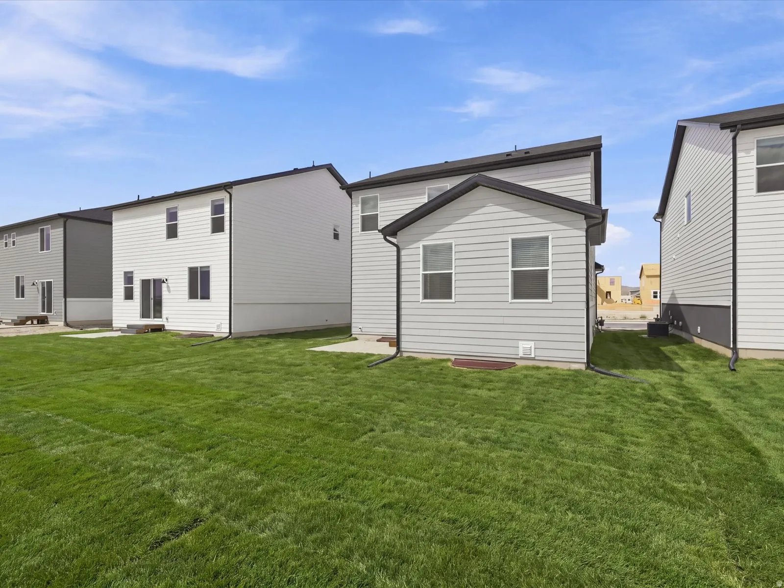 **DISCLAIMER** Landscape is only included in the front of the home. Expansive green lawn with a newly constructed exterior featuring light gray siding and black trim details