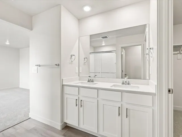 Double vanity with white cabinetry, integrated sinks, white countertops, and a wide wall-mounted mirror