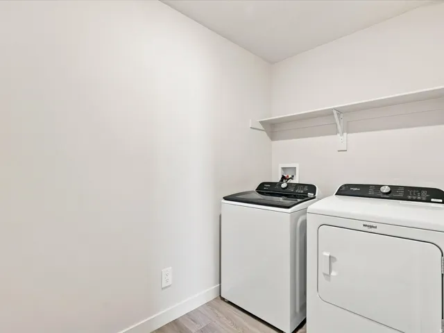 Dedicated laundry space with wood-finish flooring and integrated shelving