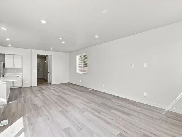 Open concept living area featuring light wood-finish flooring, recessed lighting, and a kitchen with white cabinetry and a built-in breakfast bar