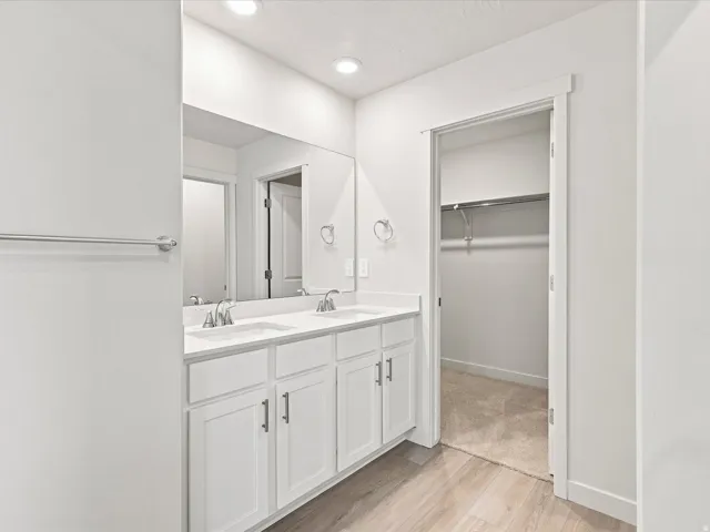 Dual vanity featuring white shaker-style cabinetry, undermount sinks, and a full-width mirror