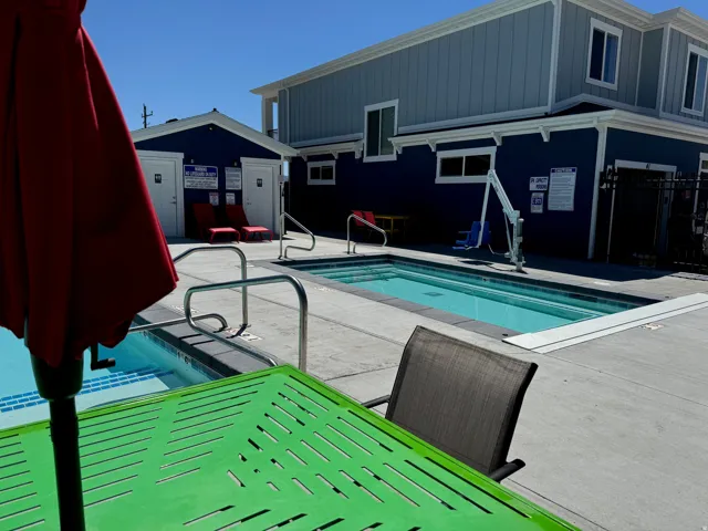 Pool area featuring two distinct pool sections, surrounding concrete decking, and modern architectural buildings