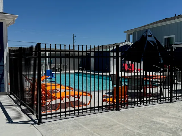 Outdoor swimming pool with surrounding black metal fencing and concrete decking
