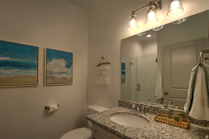 Vanity with a granite-style countertop, undermount sink, and polished chrome faucet
