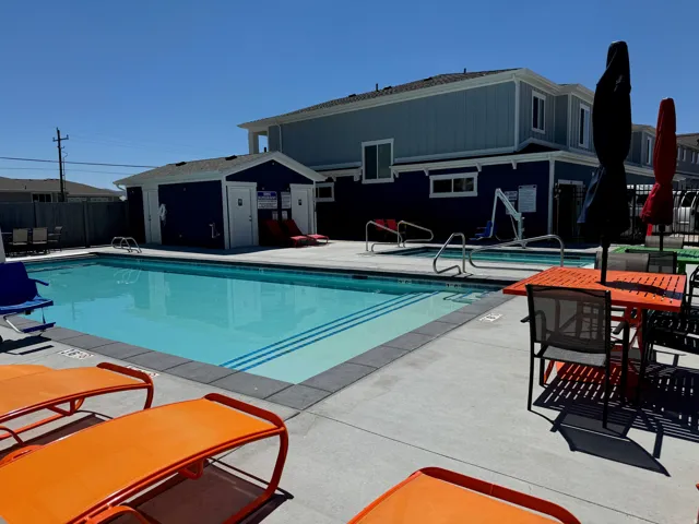 Outdoor swimming pool with concrete surround, integrated pool steps, and surrounding structures