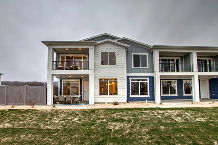 Multi-level exterior with covered patio, second-story balcony, white trim windows, and two-tone siding