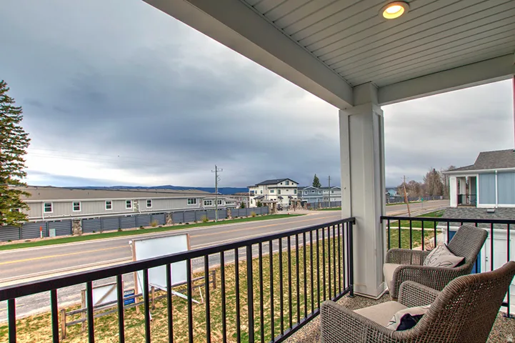 Covered balcony with recessed lighting, white columns, and black metal railings