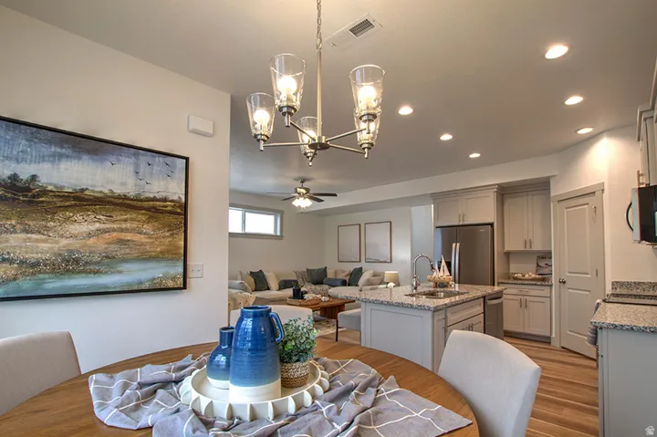 Open-concept living area with wood-finish flooring, recessed lighting, and a contemporary chandelier