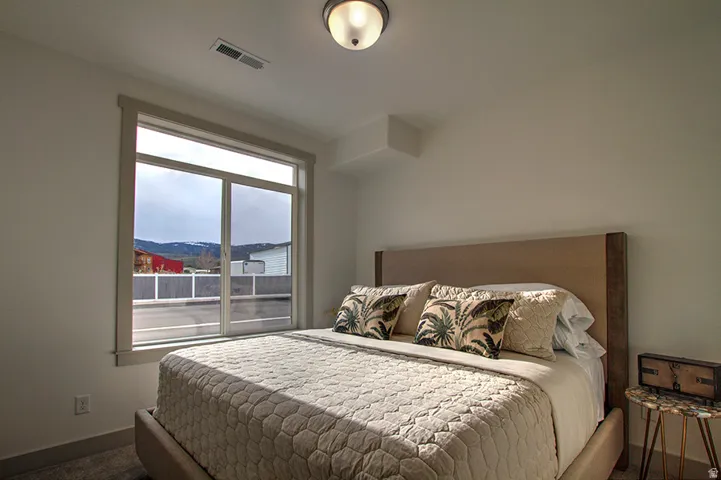 Expansive window with mountain scenery, plush carpet flooring, recessed ceiling lighting, and a neutral color palette