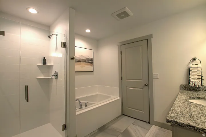 Glass-enclosed shower with subway tile surround, recessed lighting, and built-in shelving