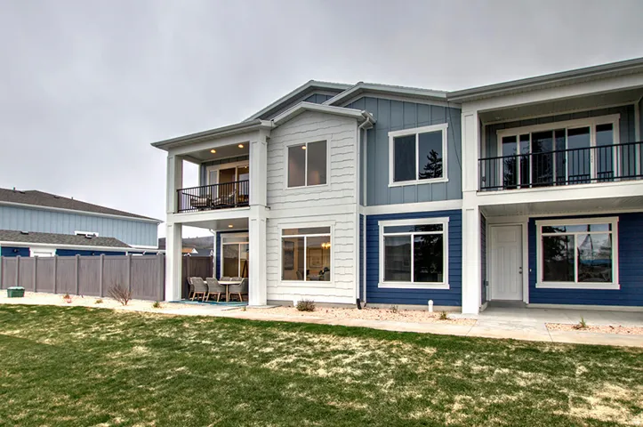 Multi-level exterior with a covered patio, upper-level balcony, and a combination of horizontal and vertical siding