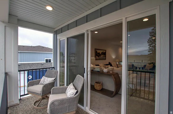Covered balcony featuring recessed lighting, a sliding glass door, and a black metal railing