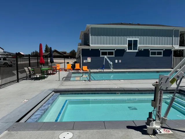 Outdoor swimming pool and spa with concrete surround and black metal fencing