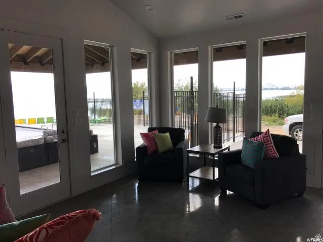 Vaulted ceiling with recessed lighting, polished concrete flooring, extensive window array, and double glass doors