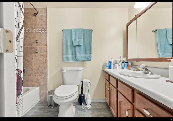 Tub/shower combination with tiled surround, functional vanity with integrated sink, wood-finish cabinetry, and framed mirrored medicine cabinet