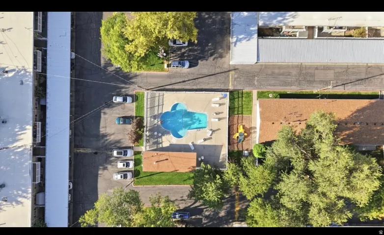 Community pool with surrounding patio, dedicated parking areas, and mature landscaping