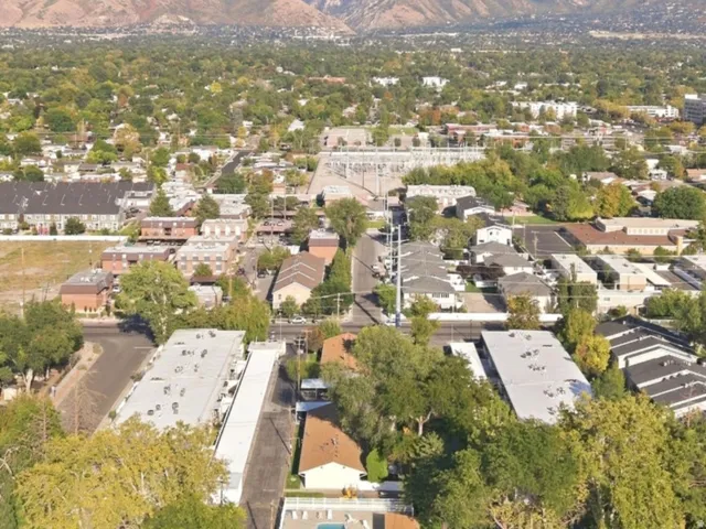 Mountain backdrop with a developed neighborhood featuring residential buildings, mature trees, and a central swimming pool