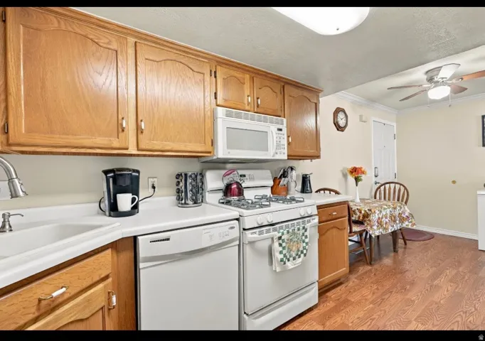 Kitchen featuring wood-finish cabinetry, white countertops, a built-in microwave, a gas range, and wood-finish flooring