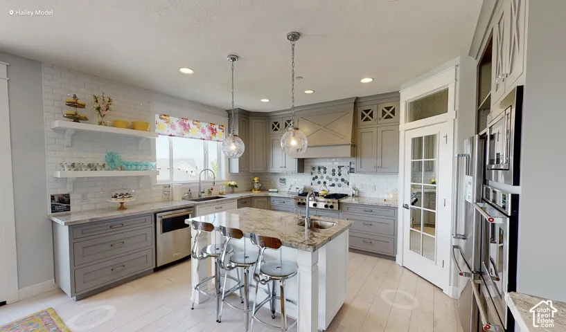 Kitchen featuring gray cabinetry, stone countertops, a large center island, stainless steel appliances, and wood-finish flooring