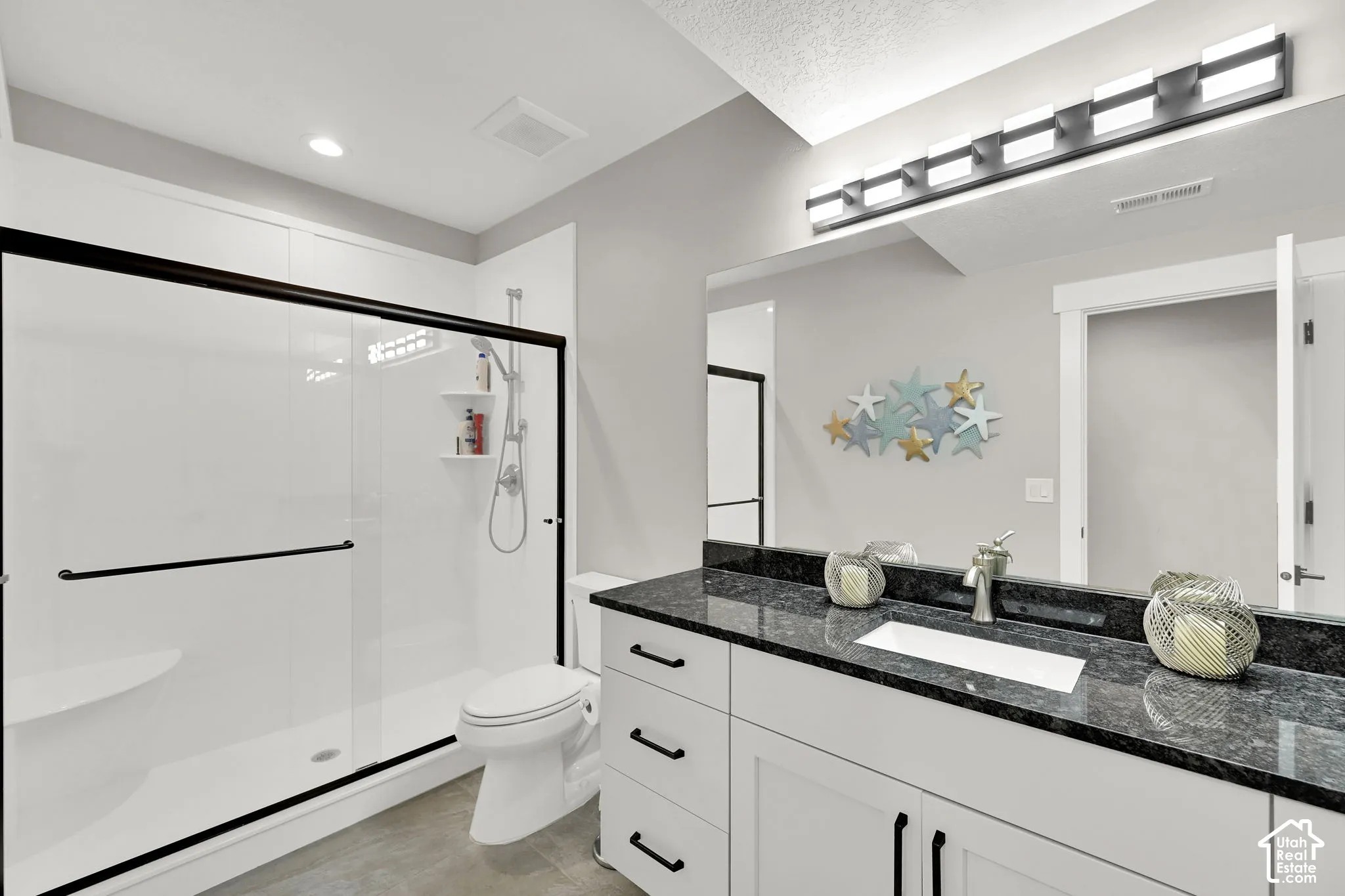 Spacious shower with black-framed glass enclosure, built-in bench, and shelving