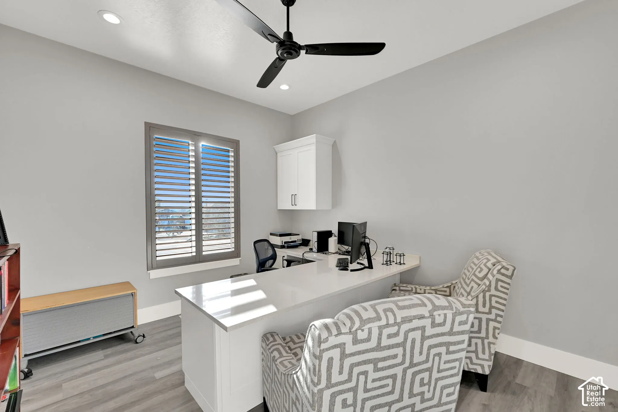 Recessed lighting, ceiling fan, wood-finish flooring, plantation shutters, and built-in desk for office.