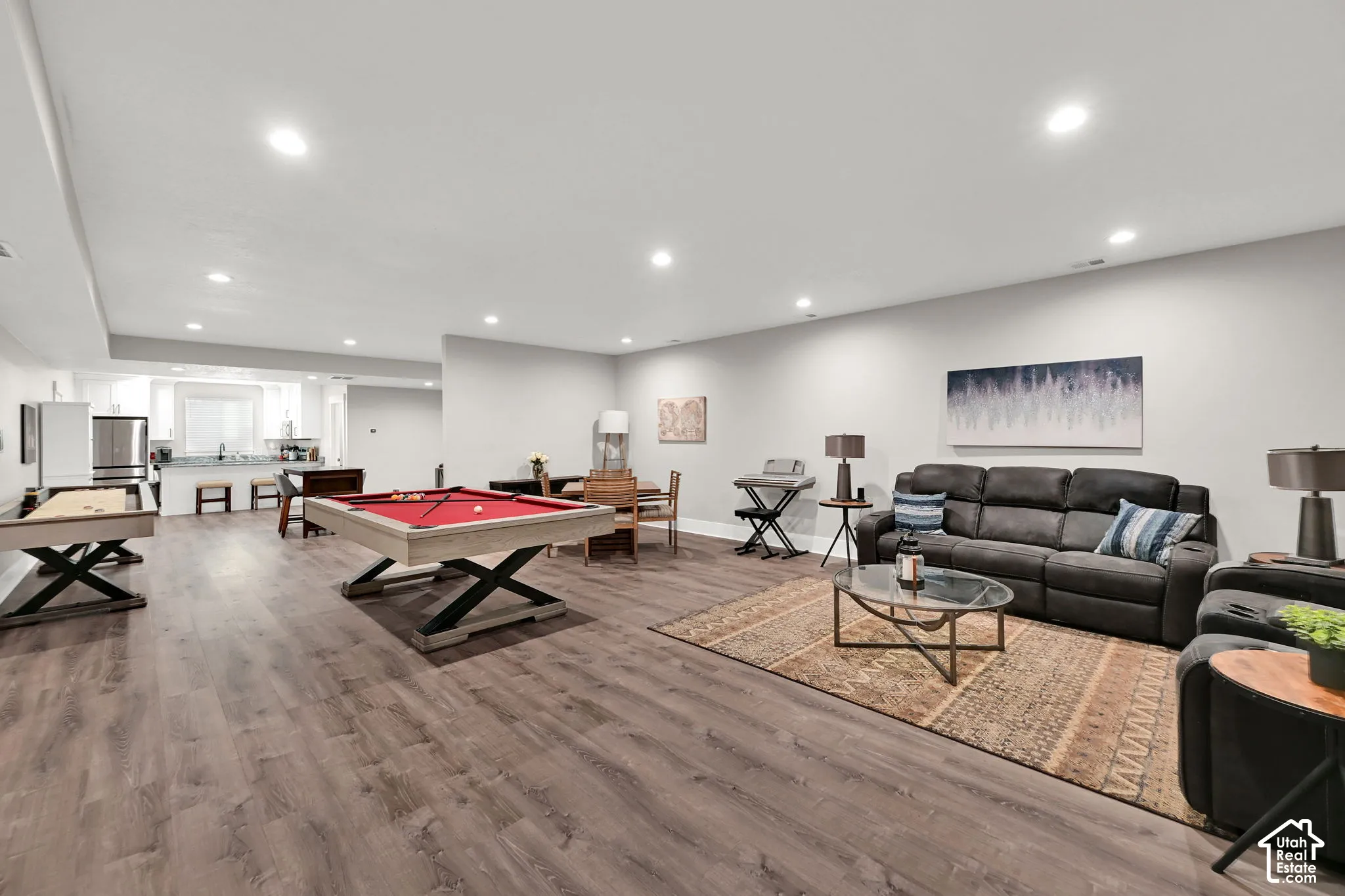 Spacious entertainment area with recessed lighting, wood-finish flooring, and a dedicated kitchen