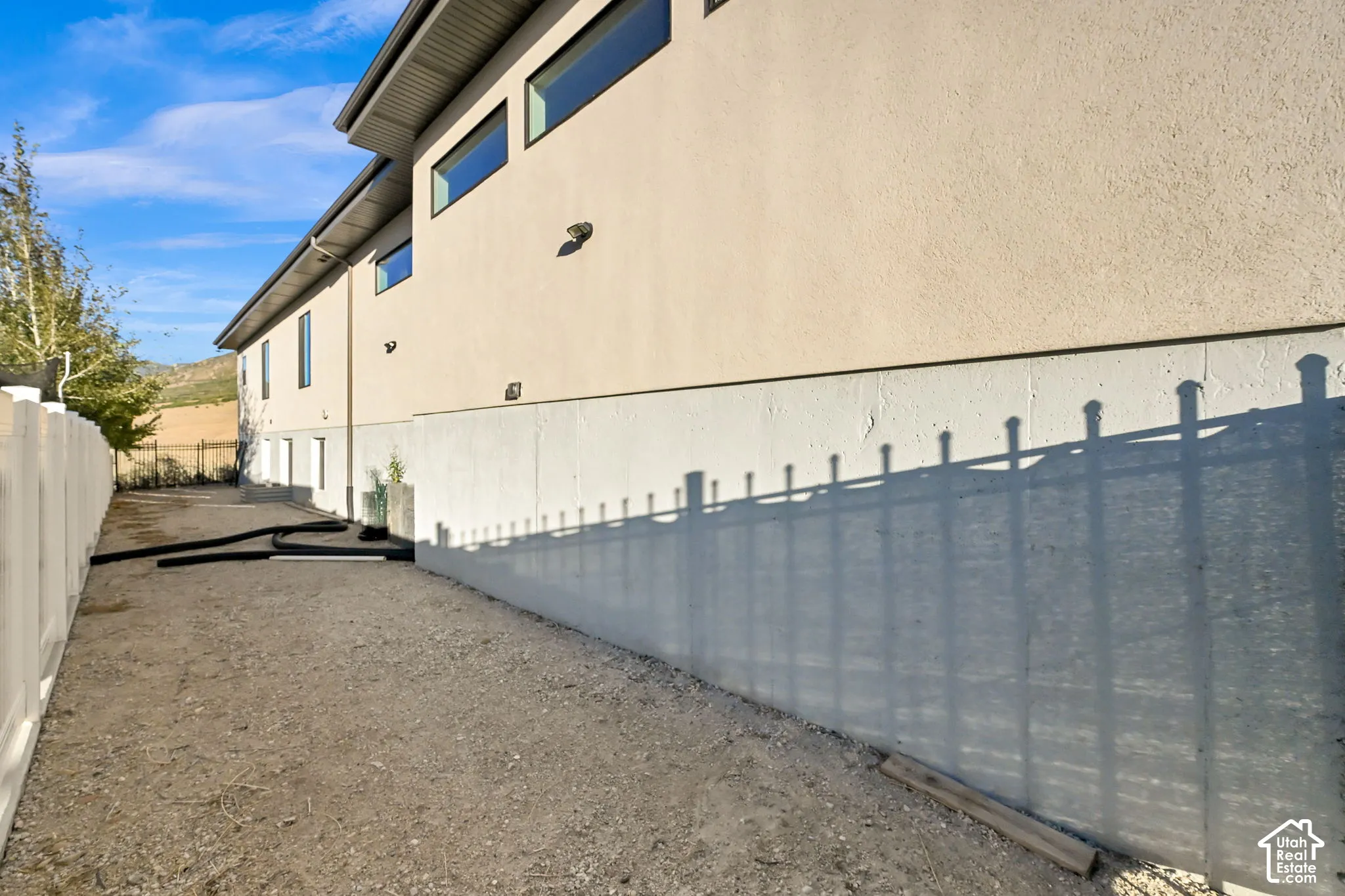 Gated RV parking. Exterior facade with multiple windows, with a black privacy gate and a gravel surface