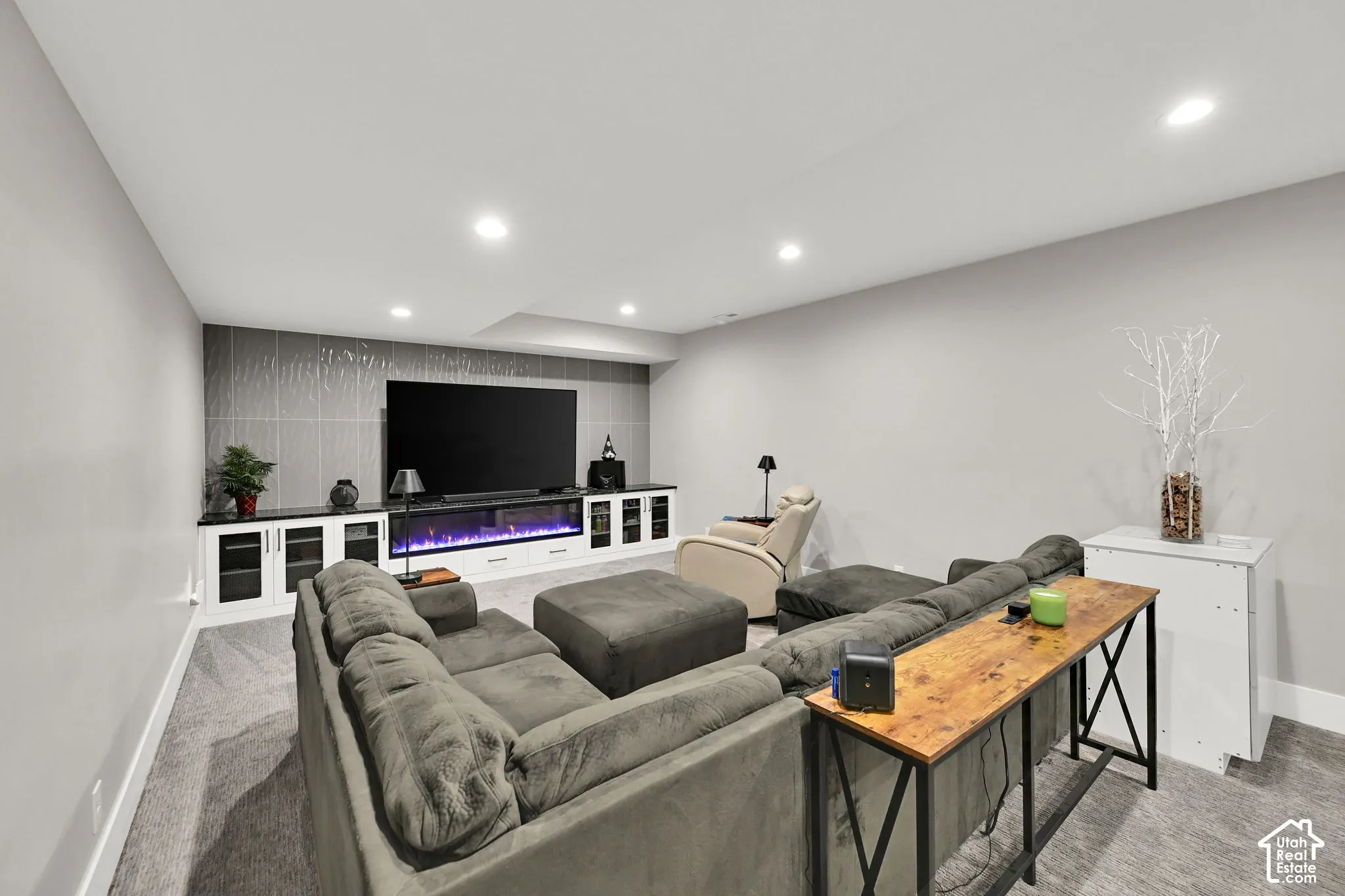 Recessed lighting, built-in entertainment center cabinets with electric fireplace, textured accent wall, and carpet flooring
