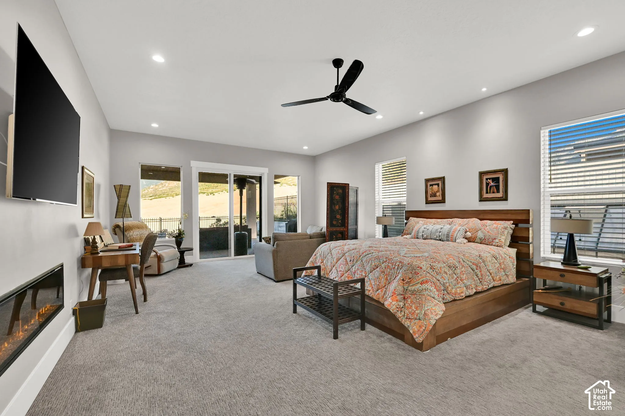 Spacious Master bedroom featuring carpeting, recessed lighting, a ceiling fan, a linear fireplace, and direct patio access through sliding glass doors