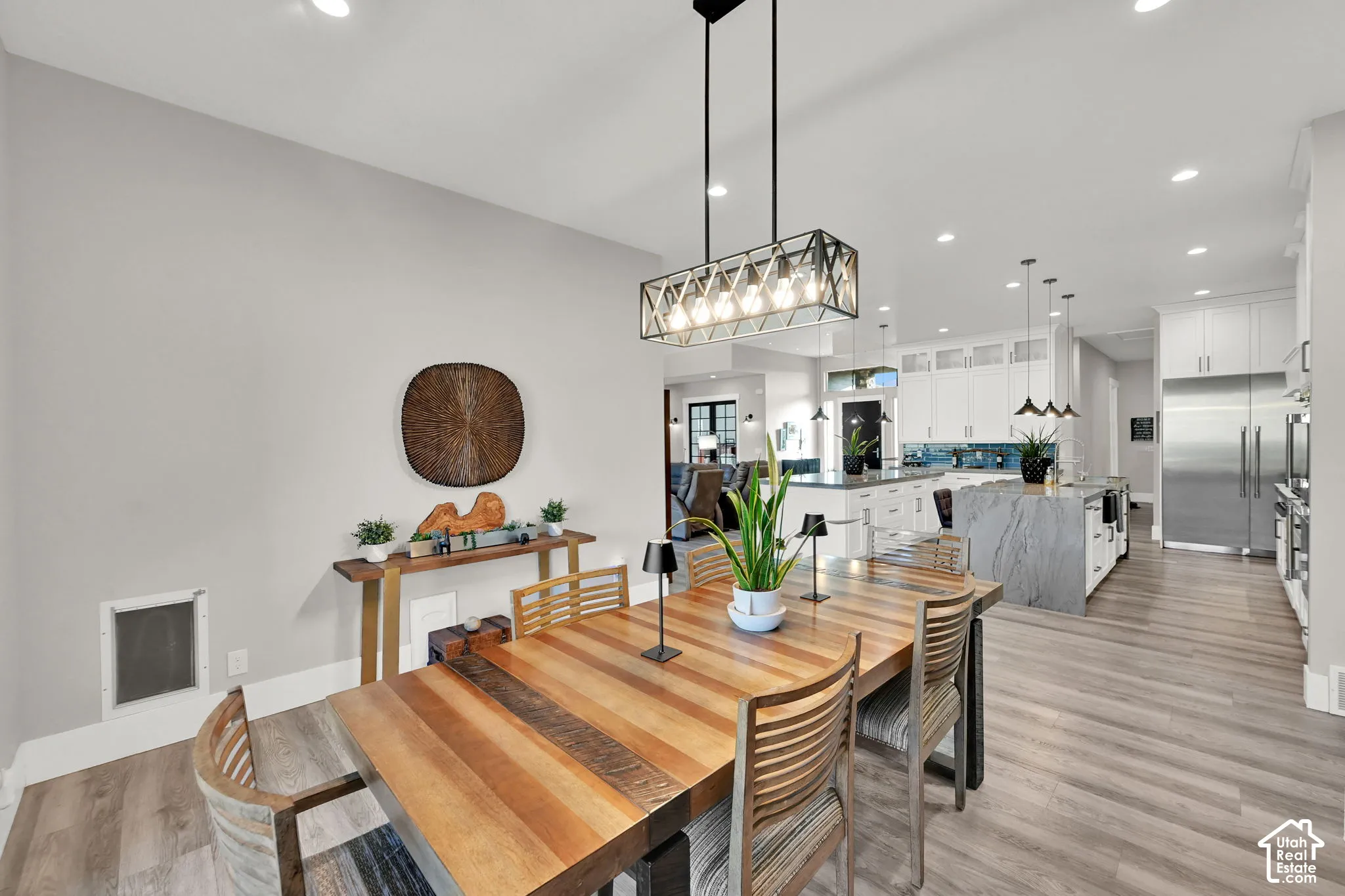 Open-concept living space featuring wood-finish flooring, recessed lighting, and a linear chandelier