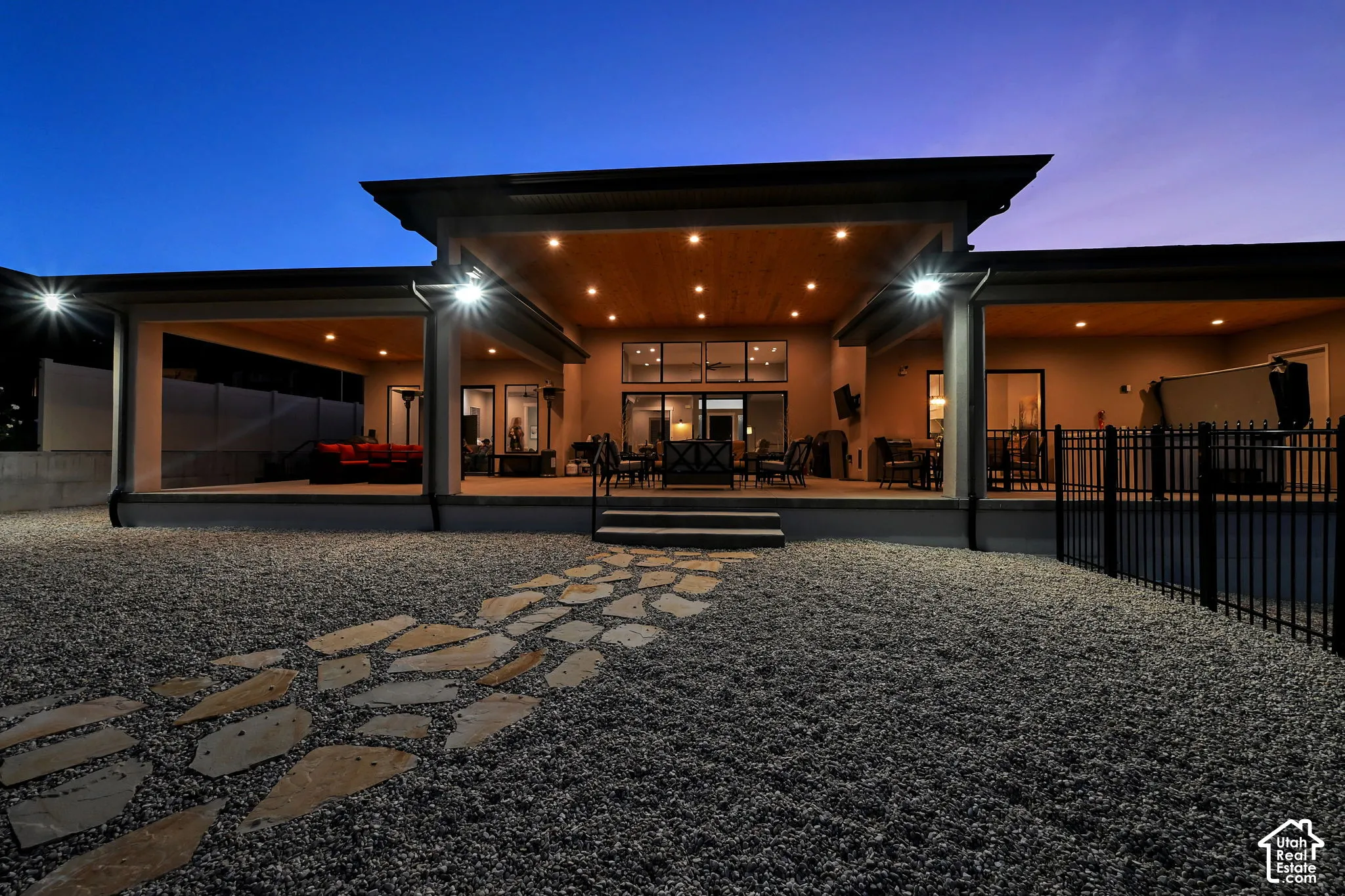 Expansive covered patio with recessed lighting, stone paver pathway, and gravel landscaping