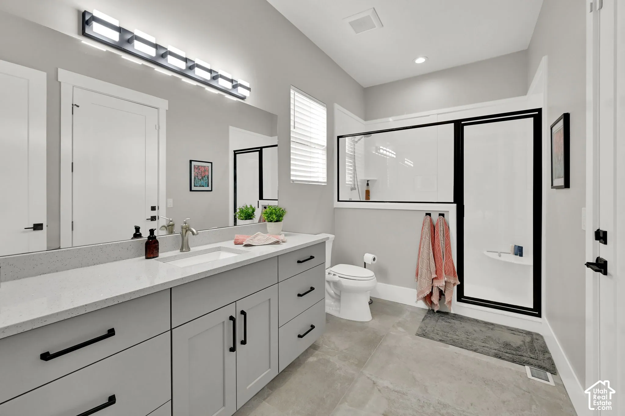 Modern bathroom featuring a single vanity with a white countertop, undermount sink, and dark hardware
