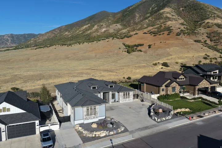 Modern dwelling featuring a stone and siding exterior, multi-gabled roof, and paved driveway