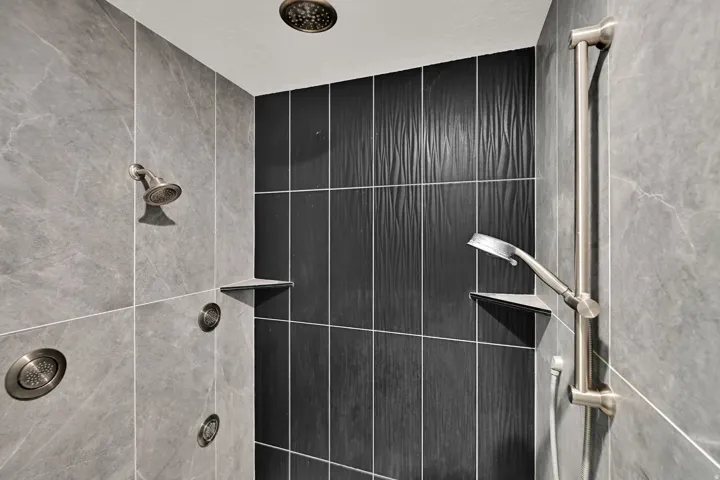 Master bath shower featuring a ceiling-mounted rain showerhead, wall-mounted showerhead, and body spray jets