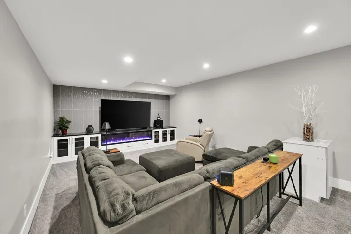 Recessed lighting, built-in entertainment center, wall-mounted electric fireplace, textured accent wall, and carpet flooring