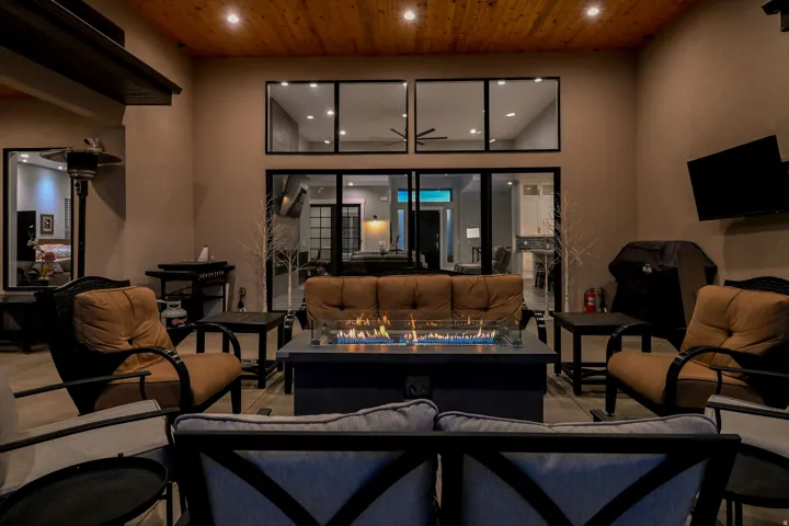 Covered outdoor patio with a wood-finish ceiling, recessed lighting, and a linear gas fire pit