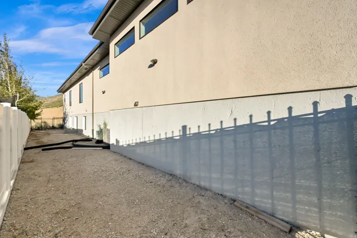 Gated RV parking. Exterior facade with multiple windows, a white privacy fence, and a gravel surface