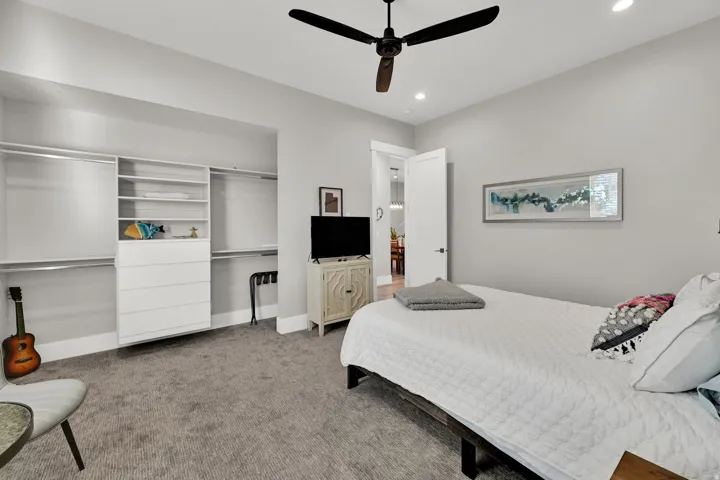 Integrated closet system with shelving and drawers, ceiling fan with integrated lighting, recessed lighting, and wall-to-wall carpeting