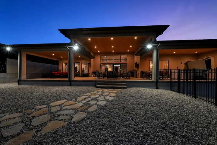Expansive covered patio with recessed lighting, stone paver pathway, and gravel landscaping