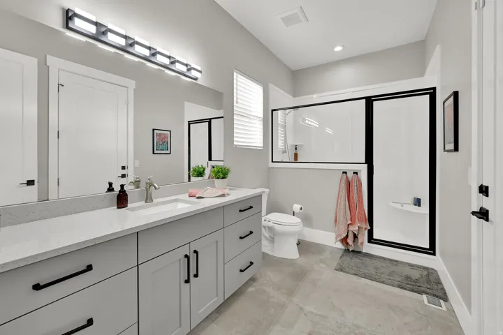 Modern bathroom featuring a single vanity with a white countertop, undermount sink, and dark hardware